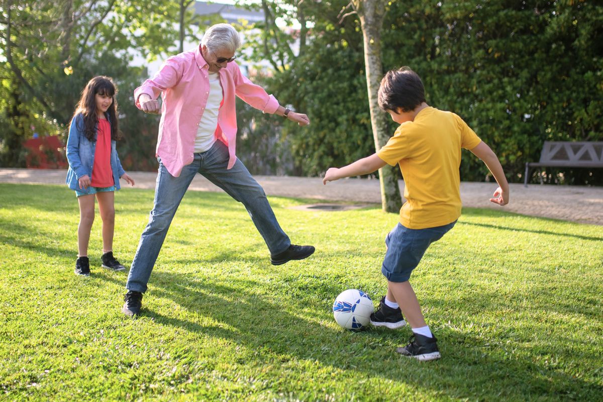 Family playing soccer together outside during active outdoor family fun.