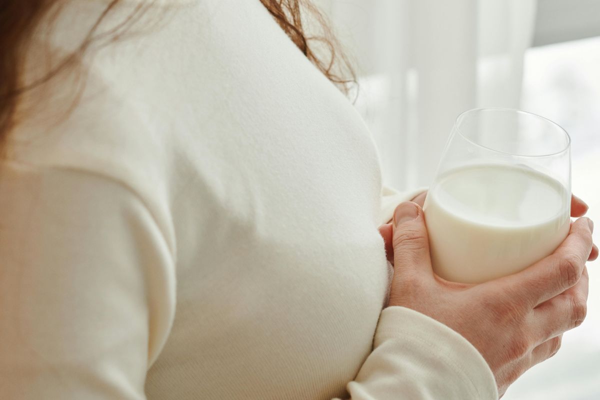 Pregnant woman holding a glass of milk, highlighting prenatal nutrition and healthy pregnancy habits.