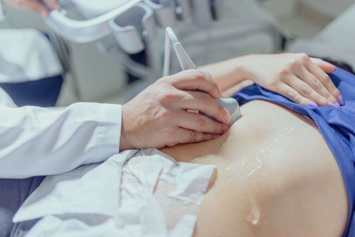 Doctor performing an ultrasound scan on a pregnant woman’s belly during a prenatal checkup.