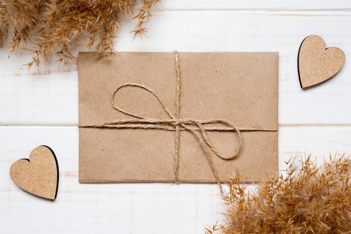 Kraft paper envelope tied with twine and surrounded by wooden heart decorations.