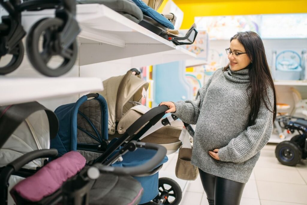 Pregnant woman shopping for a stroller in a baby store.