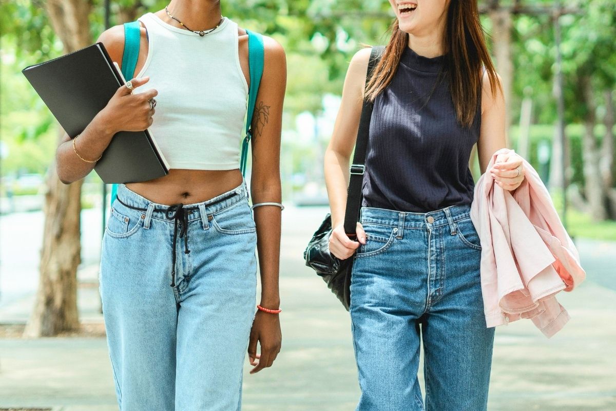 Two teenagers walking together with backpacks and casual clothes.