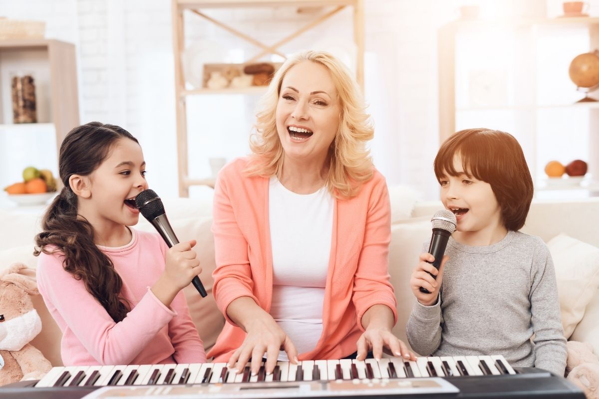 Mother playing a keyboard while her two children sing into microphones at home.