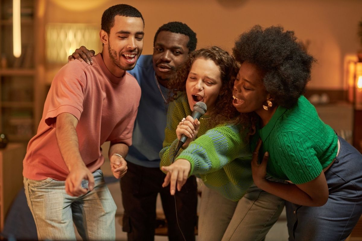 Four friends singing karaoke together and sharing a joyful moment.