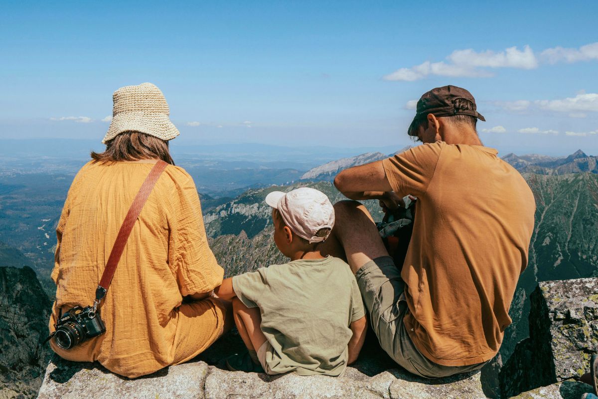 Family sitting on mountain viewpoint during Canada family vacation.