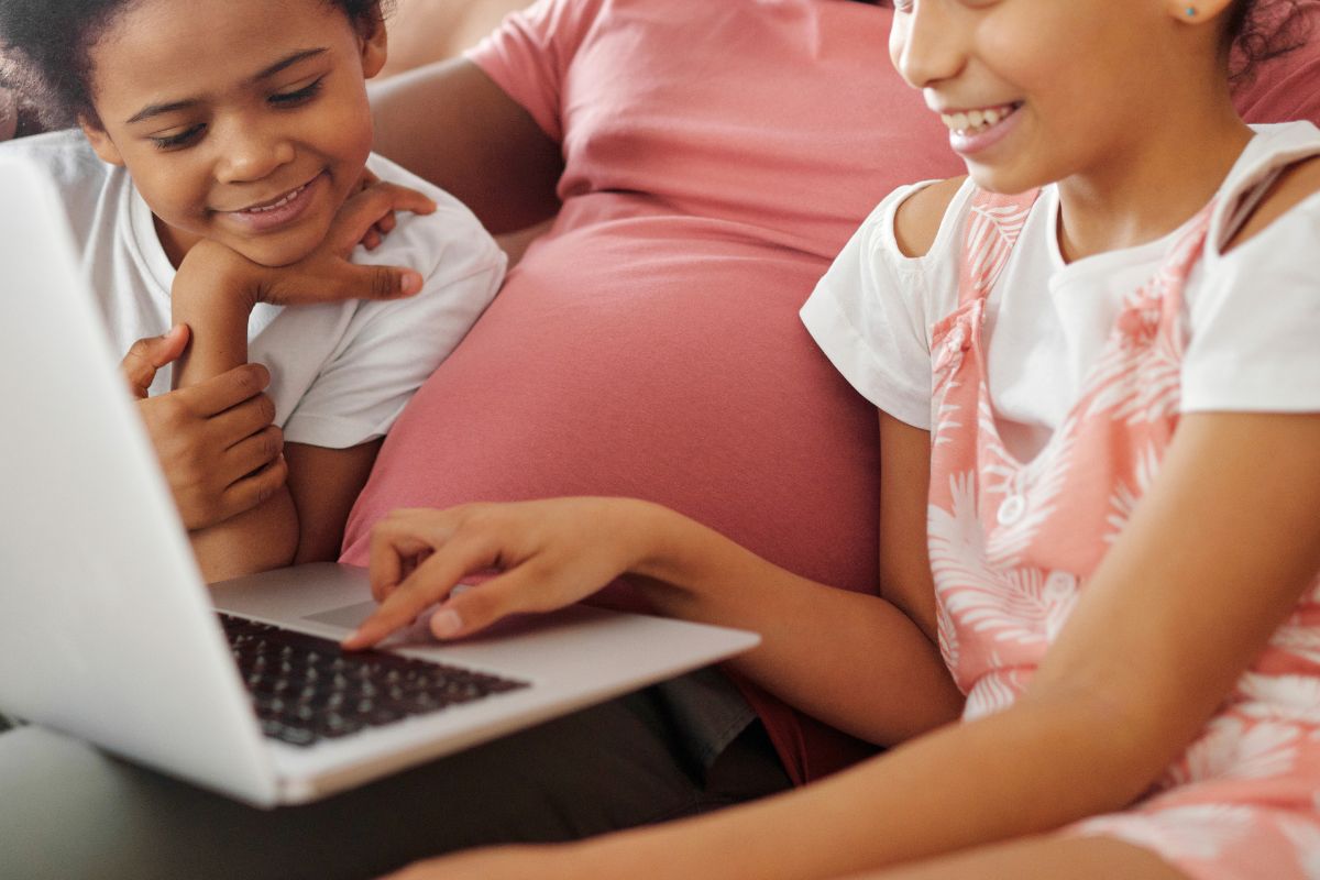 Parent guiding two children as they use a laptop and learn safe AI habits.