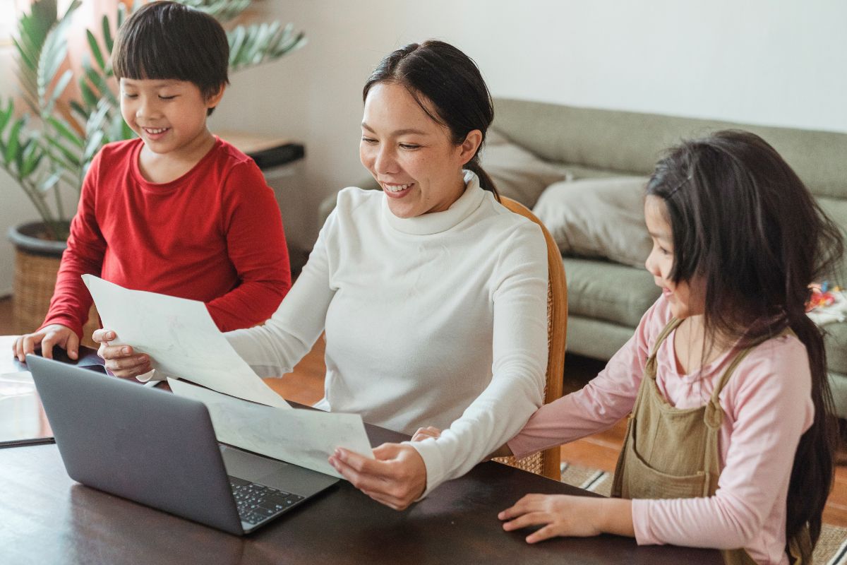 Mother reviewing online information with two children on a shared laptop.