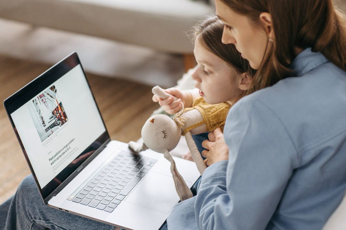 Mother supervising a young child using a laptop to support safe internet use.