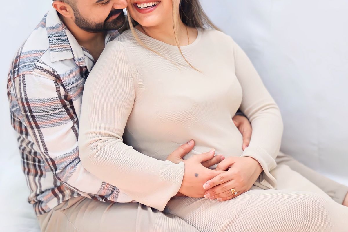 Expecting parents smiling and holding the baby bump while enjoying a sweet moment before their baby arrives.