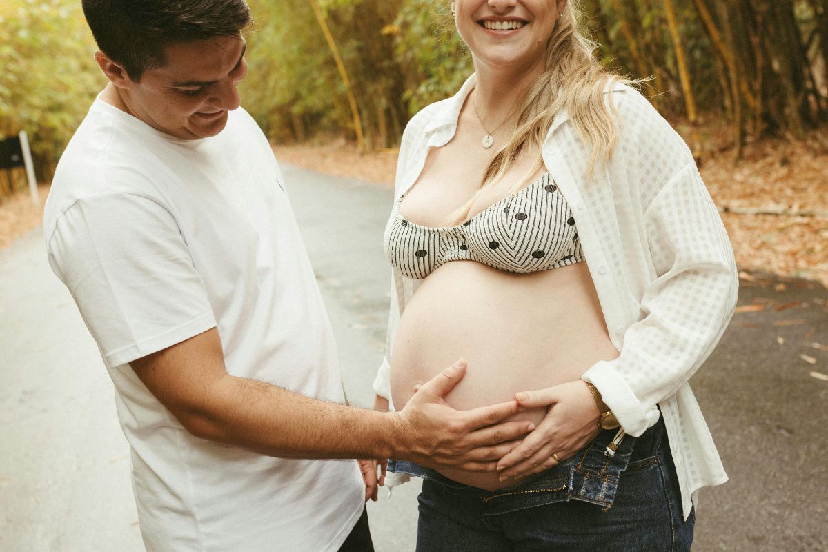 Expecting parents admiring a baby bump during a nature walk, creating special memories together before their baby's arrival.