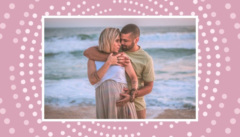 Smiling couple standing close together on a beach with a soft pink border overlay.