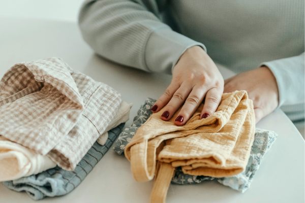 Folding baby clothes at home, showing everyday tasks in family life balance.