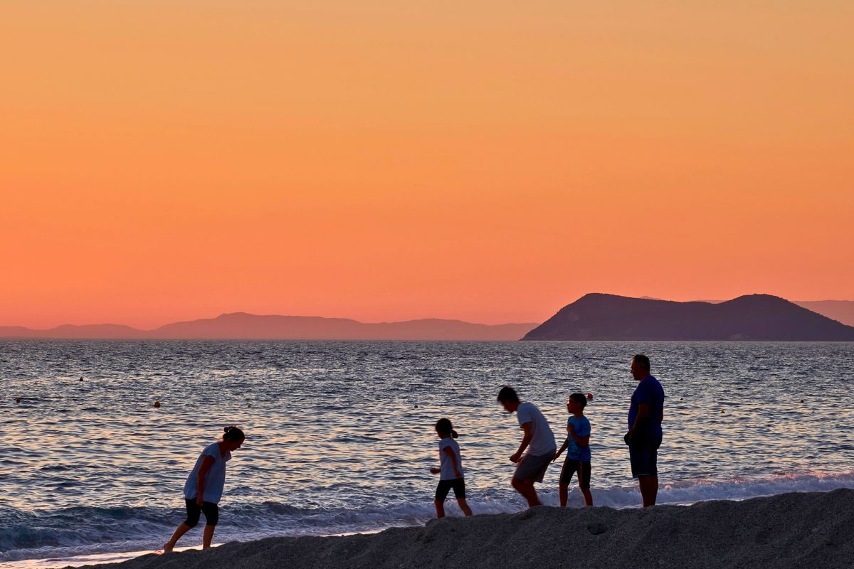 Family enjoying a beach sunset during a relaxing Canada vacation.