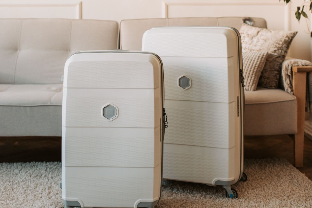 White hard shell suitcases for family travel placed in a living room ready for packing.