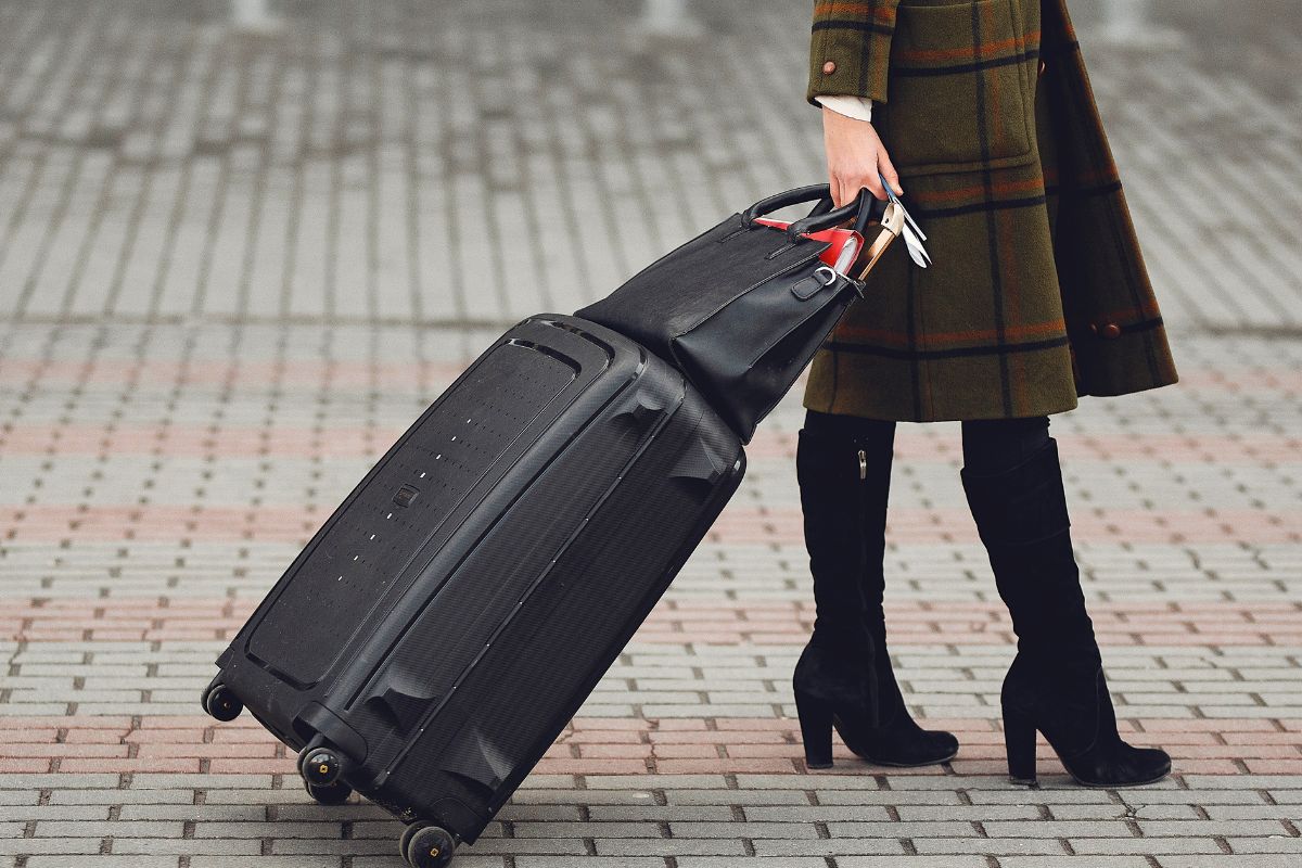 Person pulling large rolling suitcase showing practical luggage for travel.