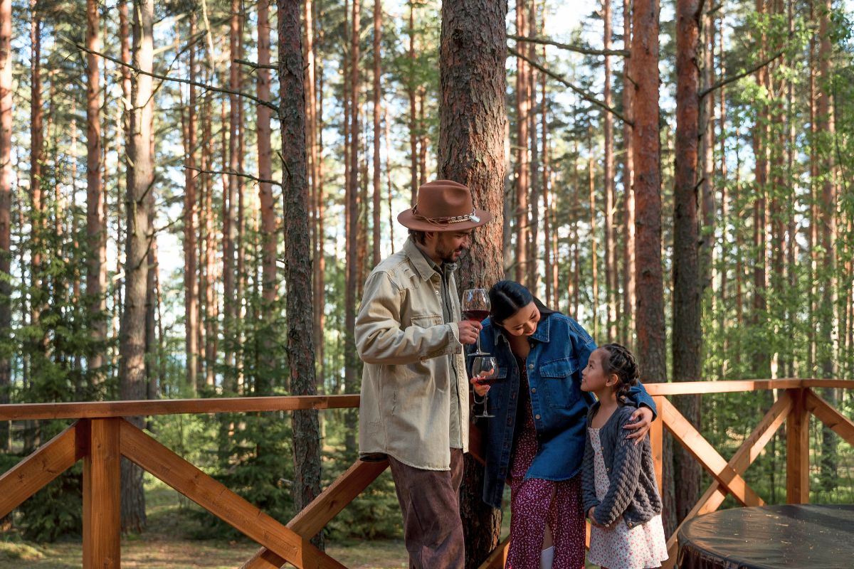 Family spending time together on a cabin deck surrounded by trees during a national park vacation.