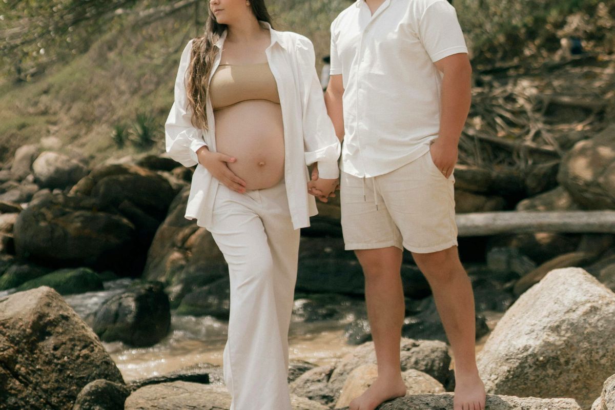 Pregnant couple walking near a stream during a relaxing babymoon getaway.