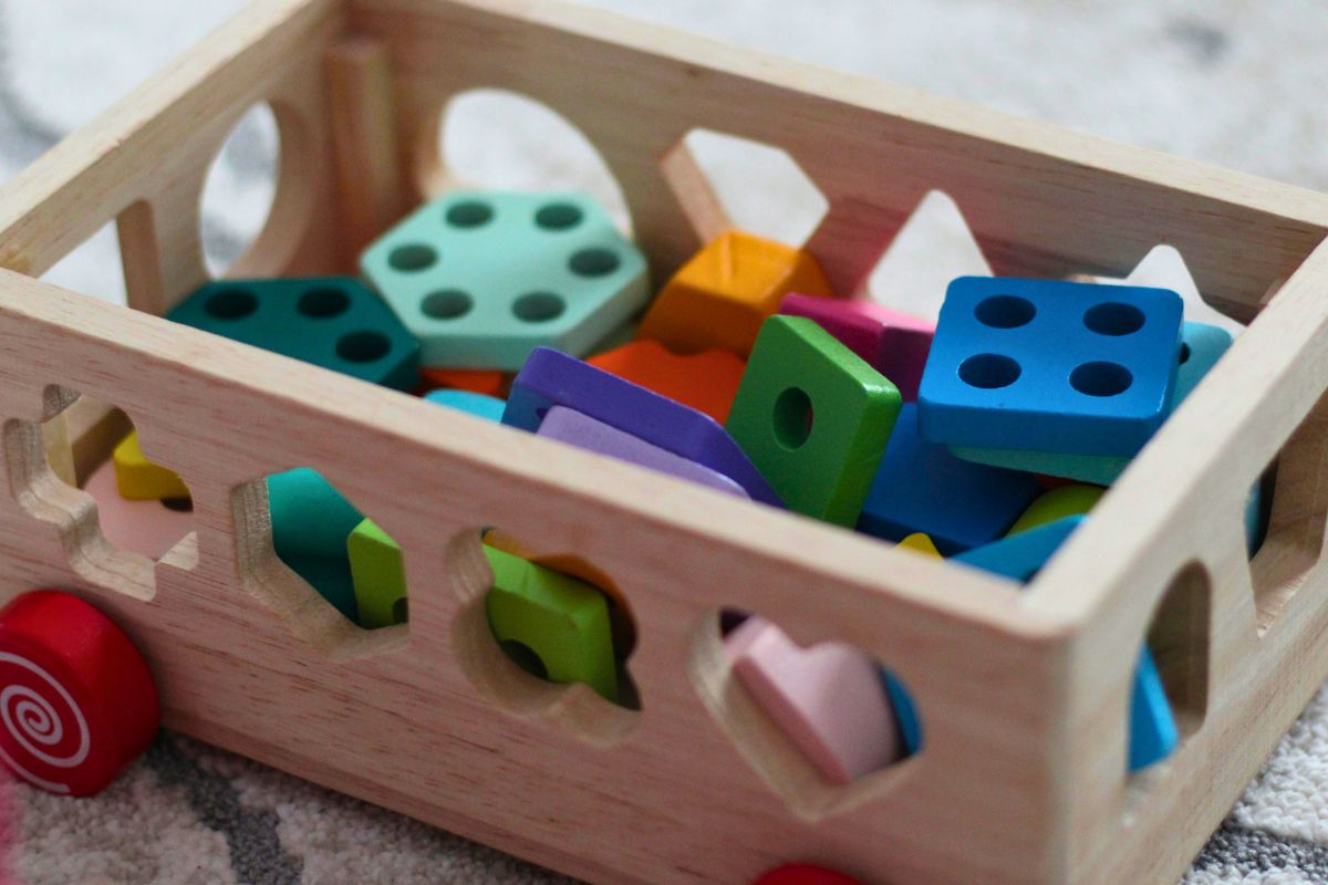 Wooden shape sorting toy with colorful blocks, a focus-building activity for toddlers.