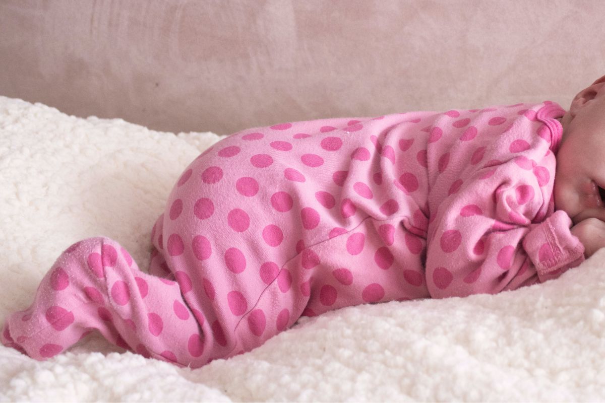 Baby in a zip-up onesie lying comfortably, ideal outfit for easy diaper changes on a plane.