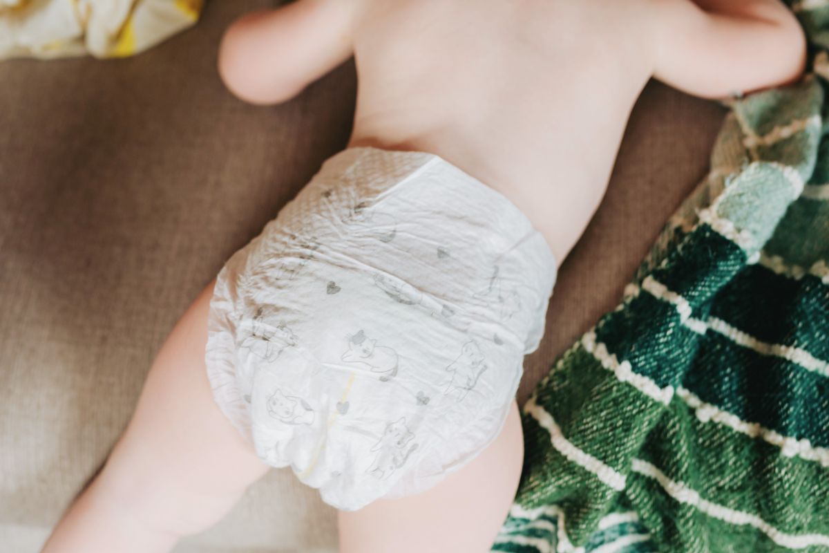 Infant lying on a surface wearing a diaper, showing simple setup for quick diaper changes while traveling.