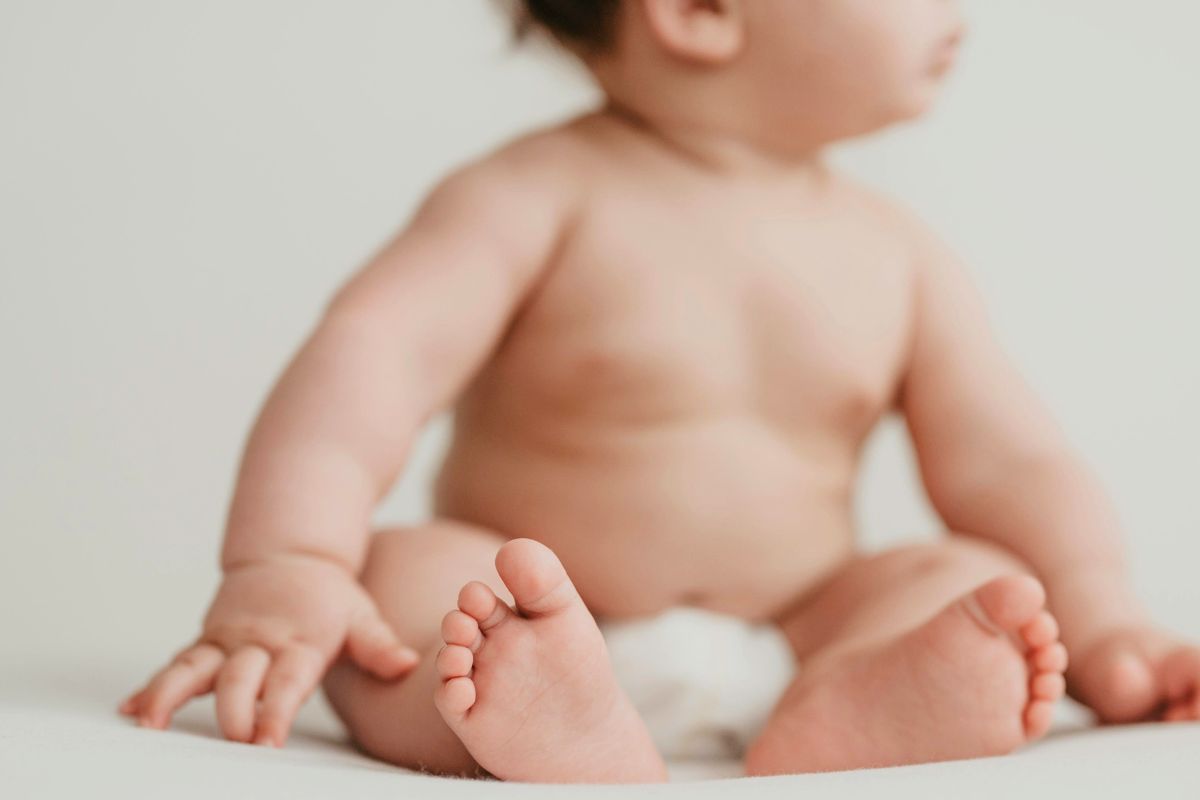 Baby sitting in a diaper, highlighting comfort and mobility for travel diaper routines.