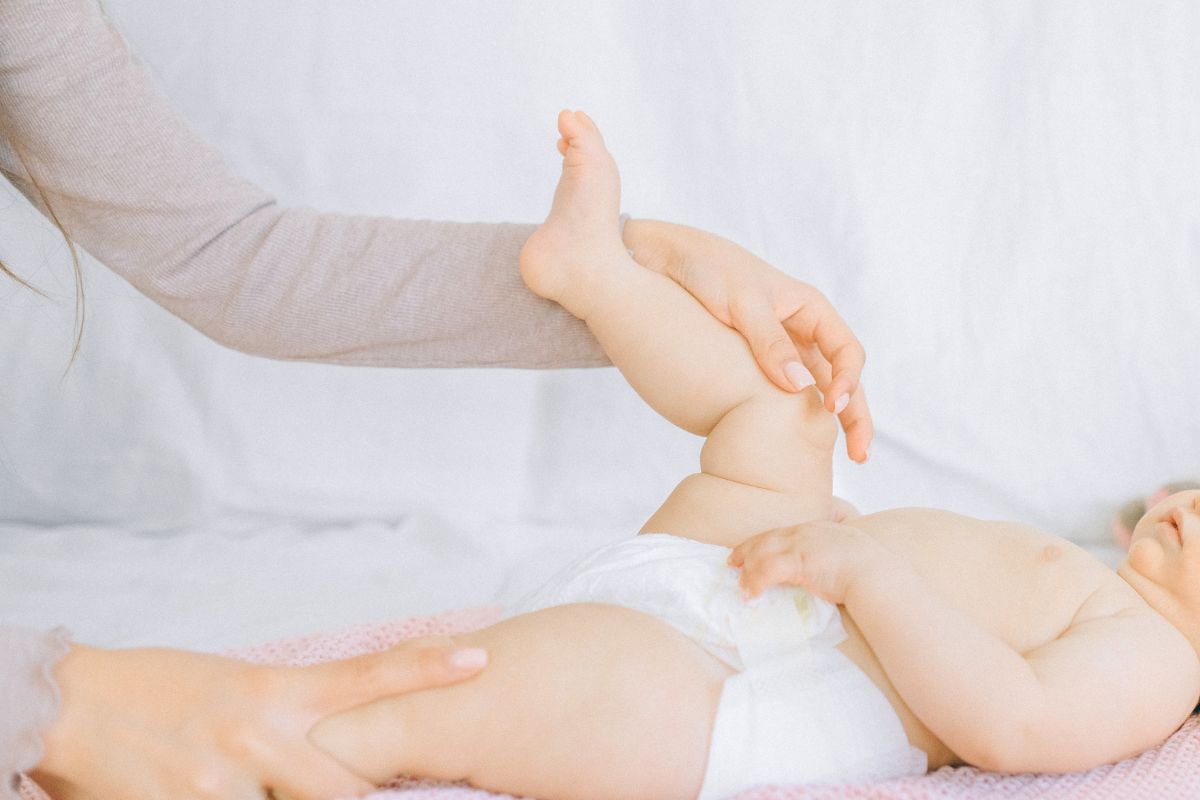 Parent lifting baby’s legs to change a diaper, demonstrating a simple diaper change technique.