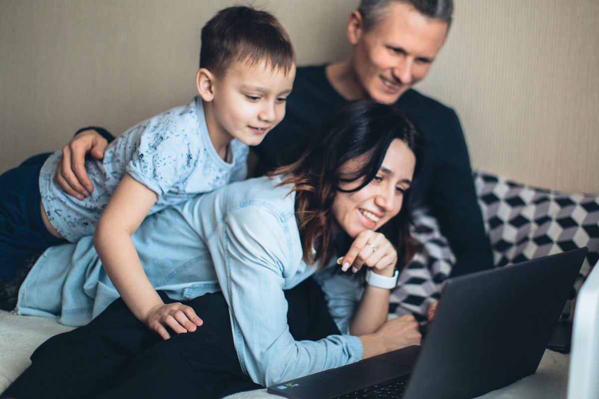 Parents and their young son looking at a laptop together while searching for family activity ideas.