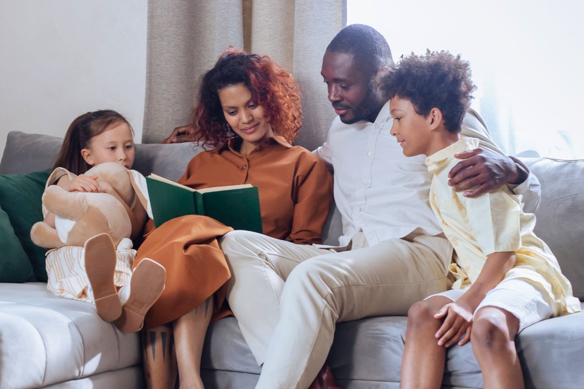 Parents reading a story with their two children during a quiet screen-free family activity.