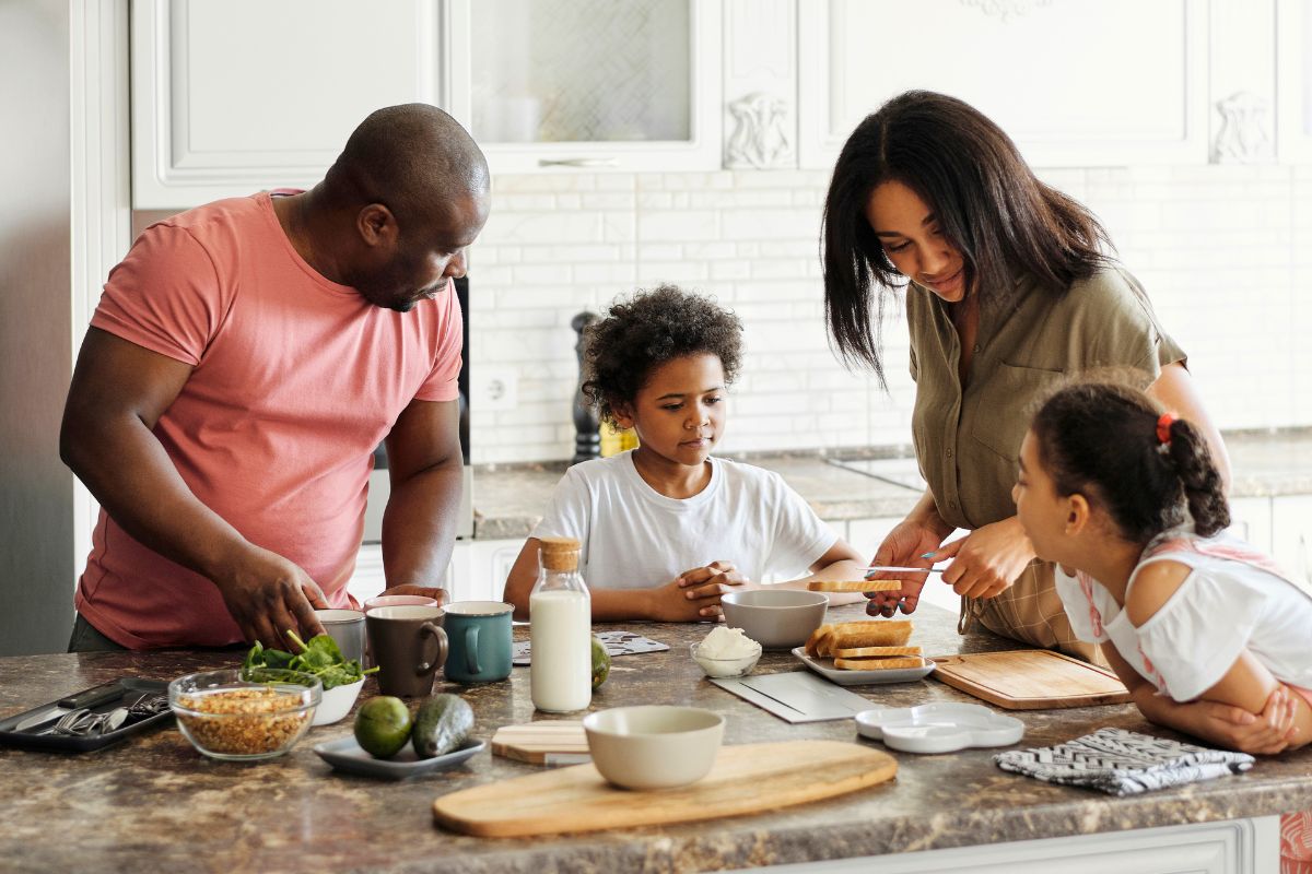 Parents and two children preparing food together during a simple family cooking activity.