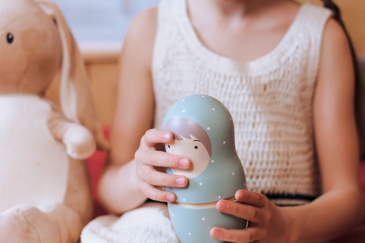 Child holding a wooden jar during quiet creative play at home.
