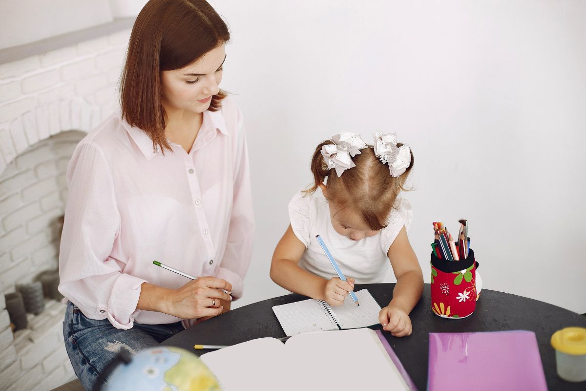 Parent helping a young child with writing practice, showing one-on-one support in early childhood care.