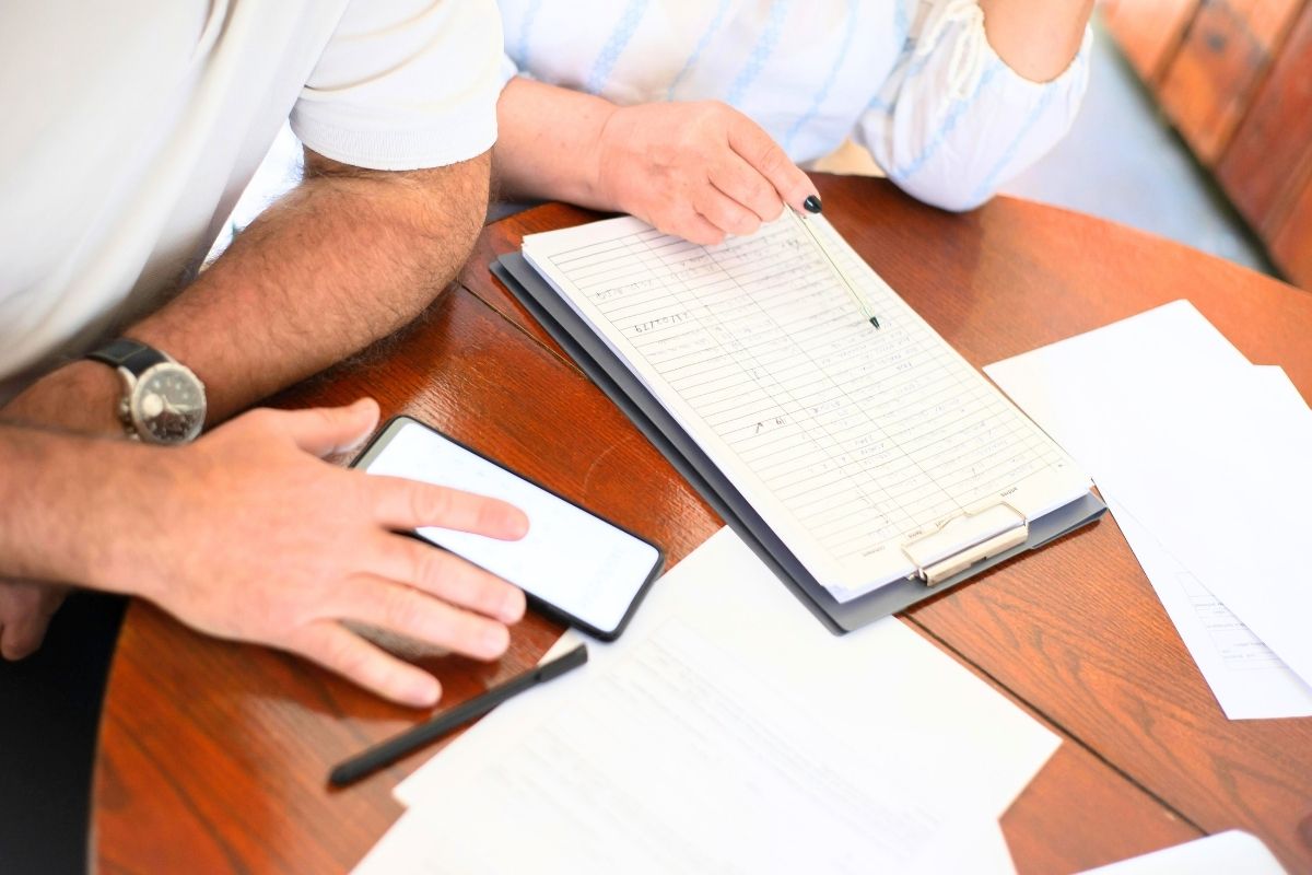 Paperwork and two adults at a desk.