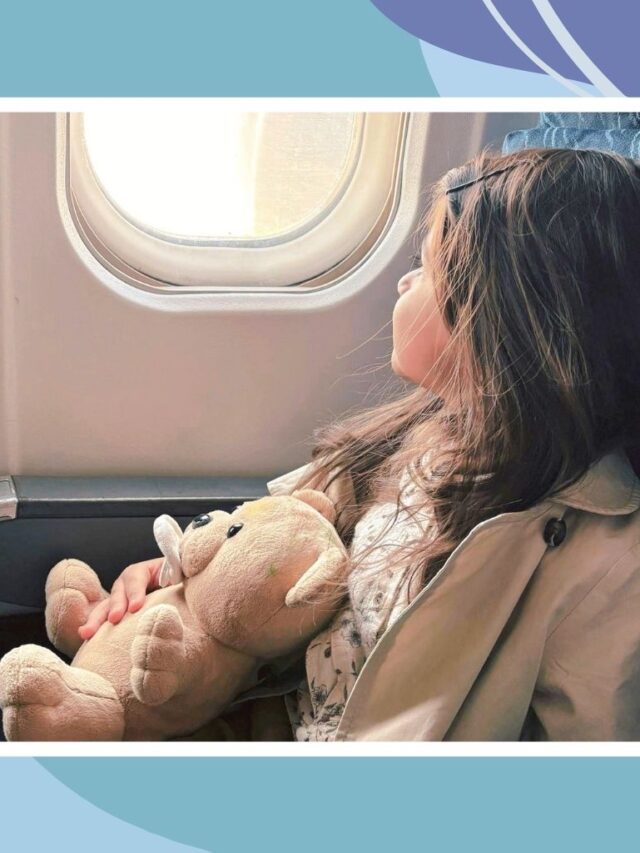 Child sitting by airplane window holding a teddy bear during a flight, capturing a calm moment while traveling with kids in Canada.