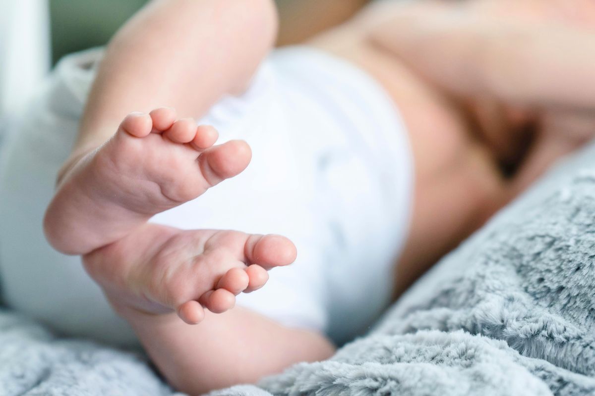 Baby relaxing in a diaper on a soft blanket during the messy but normal diaper blowout stage.