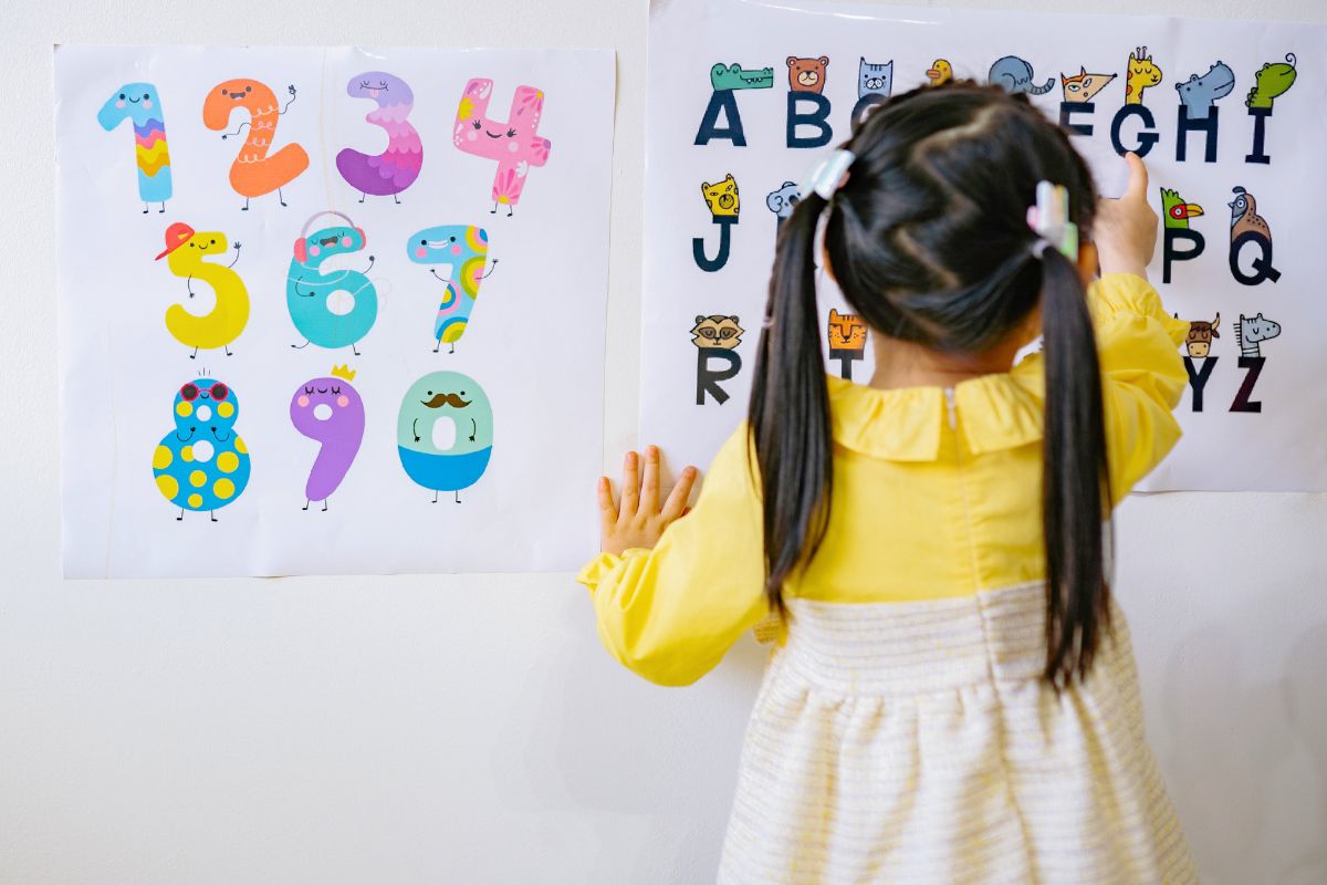 Child looking at alphabet and number posters during early preschool learning.