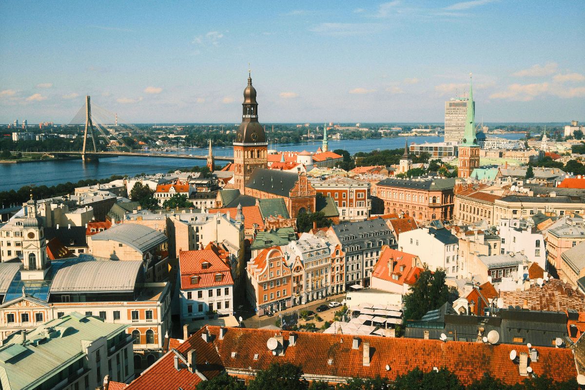 Rooftop view of Riga, Latvia, with historic European buildings, church towers, and the river in the distance.