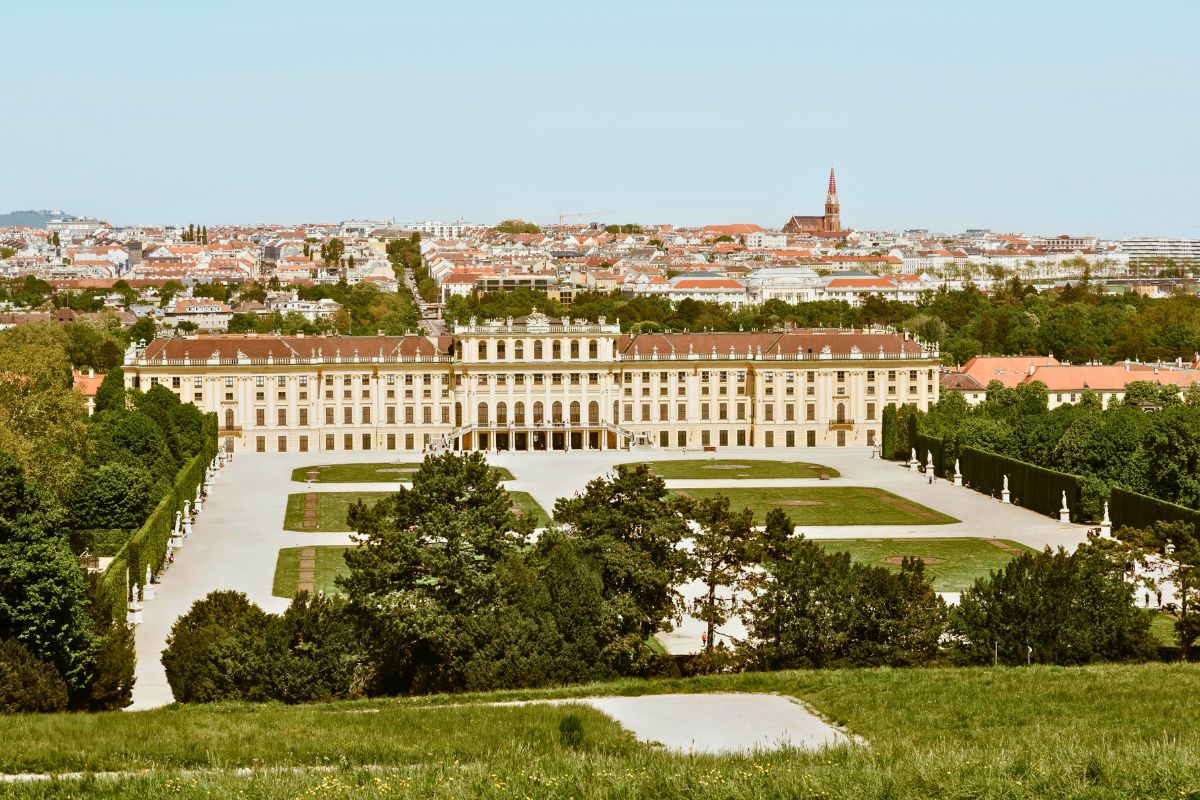 Wide view of Schönbrunn Palace in Vienna with gardens and the city in the background.