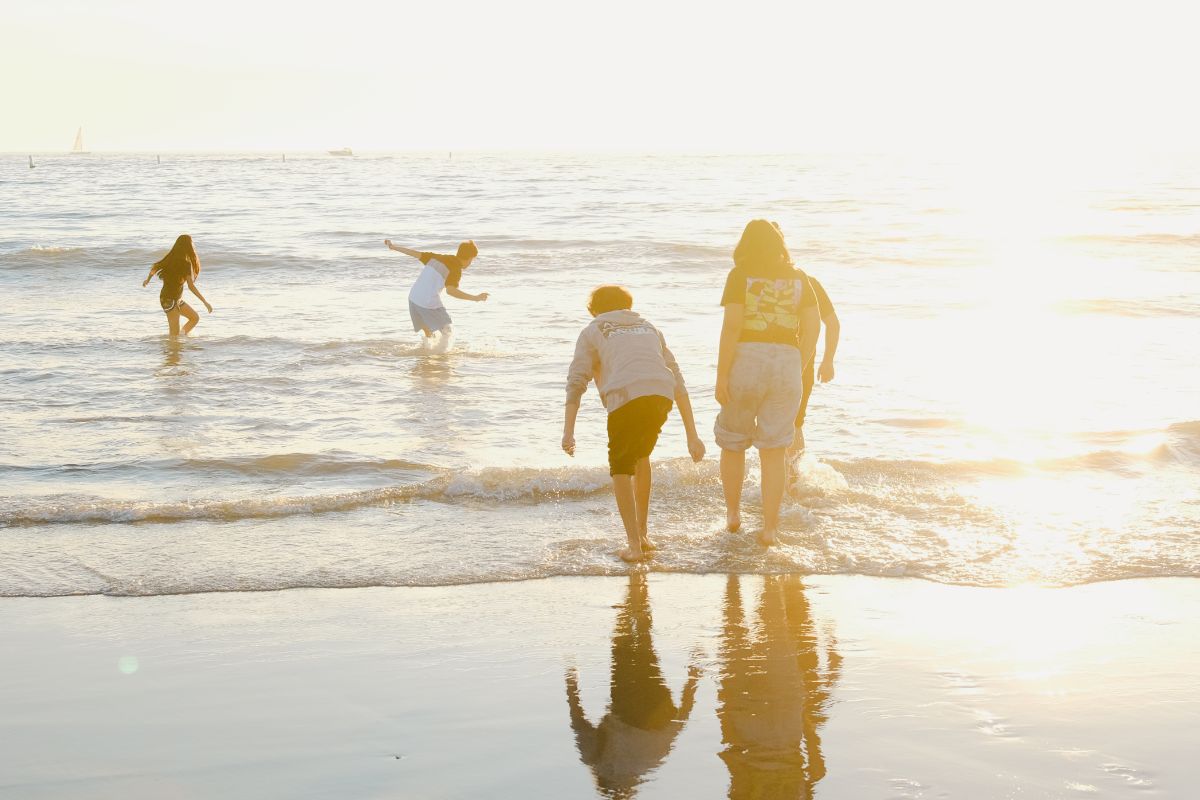 Family playing in the shallow ocean water during sunset on a family-friendly beach vacation.