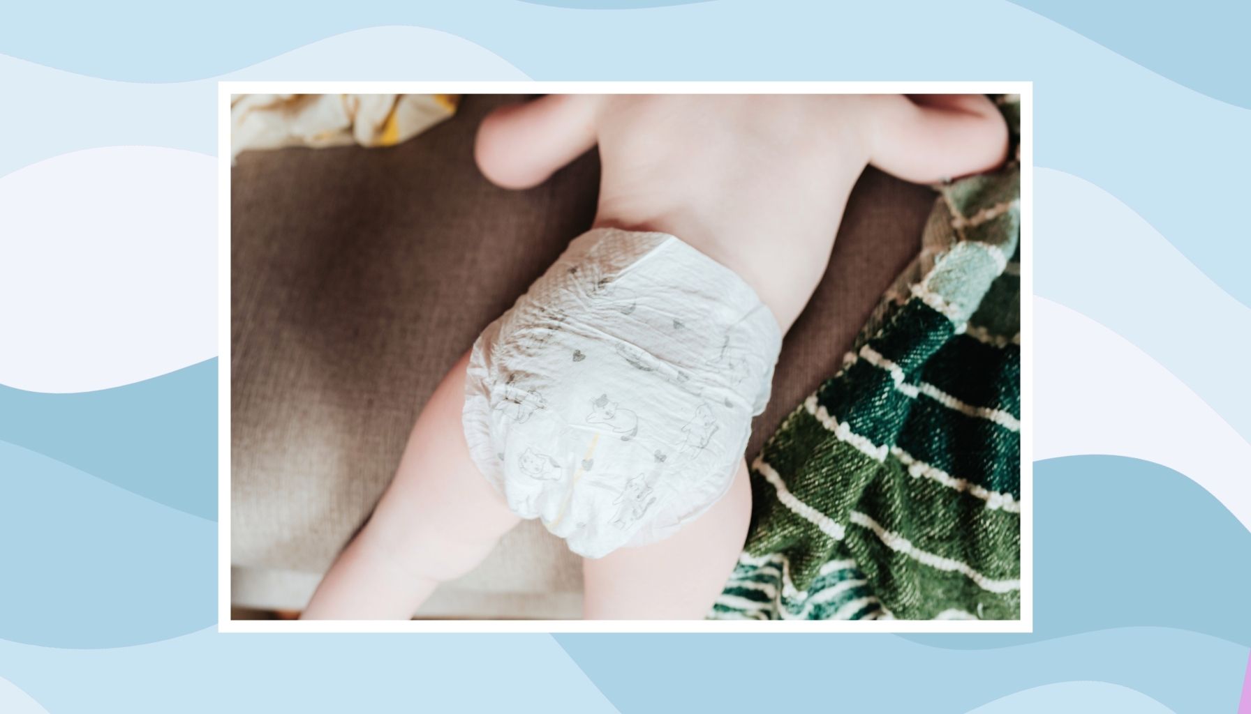 Baby on its tummy wearing a diaper with a green striped cloth.