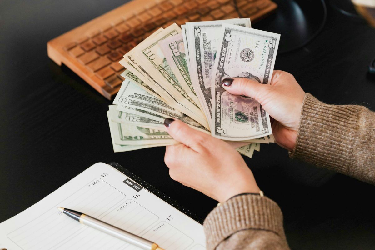 Person counting cash at a desk with planner while managing a large family budget and tracking expenses.