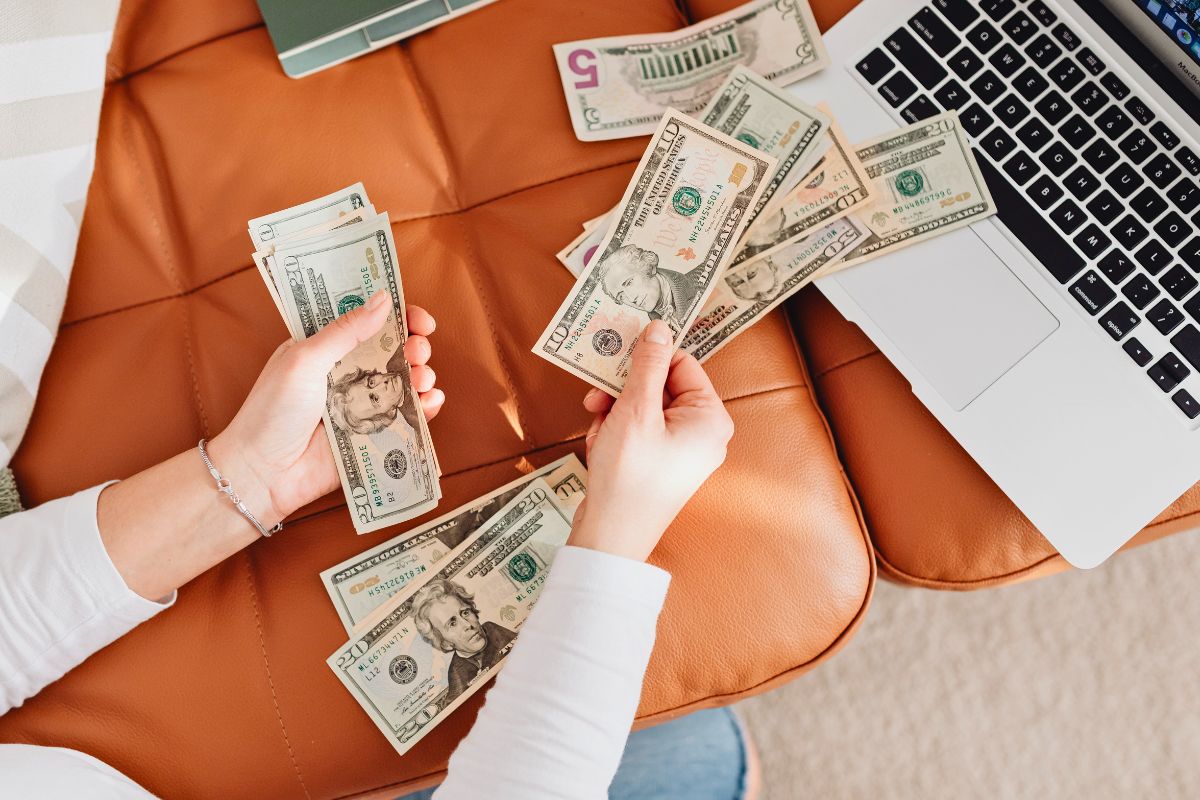Hands sorting cash near a laptop during large family budgeting and expense planning.