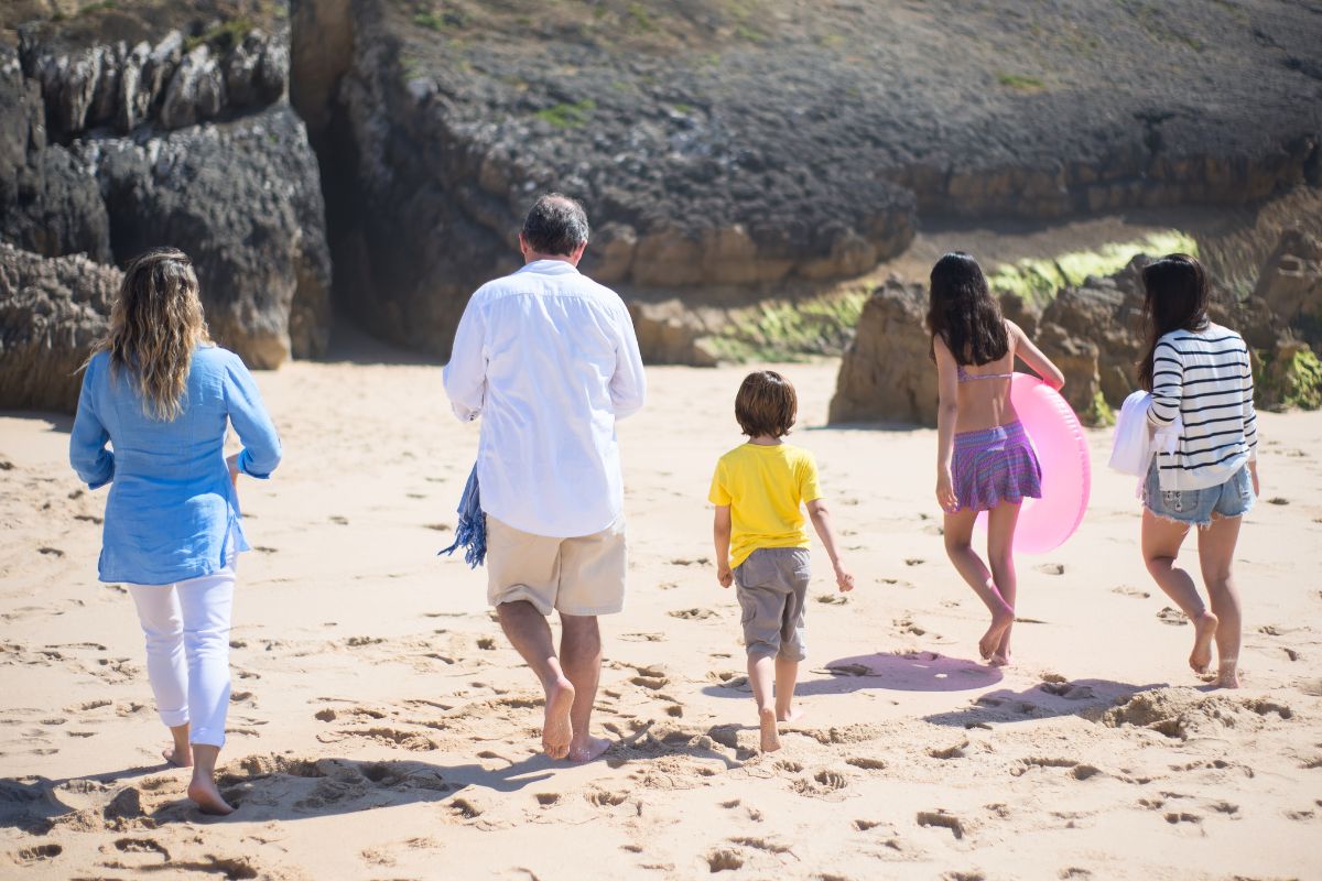 Family walking along a sandy beach in Canada, enjoying a relaxing and memorable family vacation together.