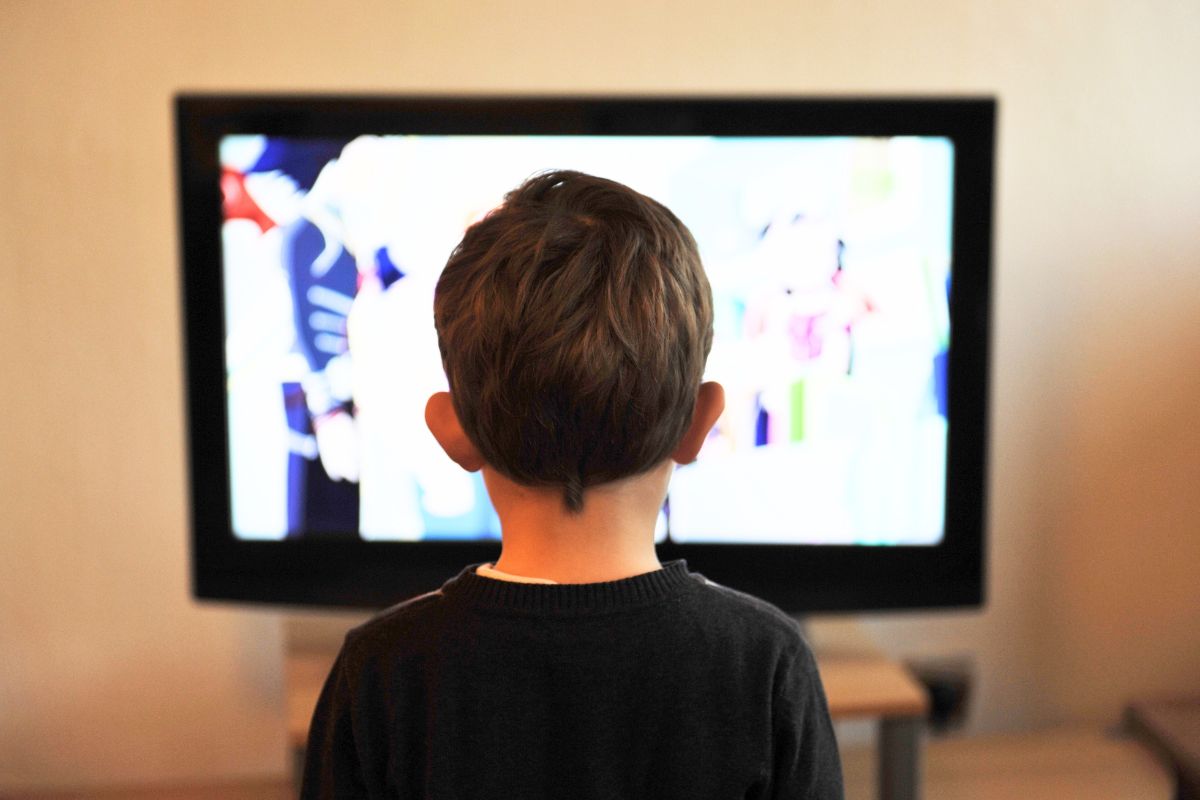 Young child watching YouTube Kids on a screen while parents manage safe screen time.