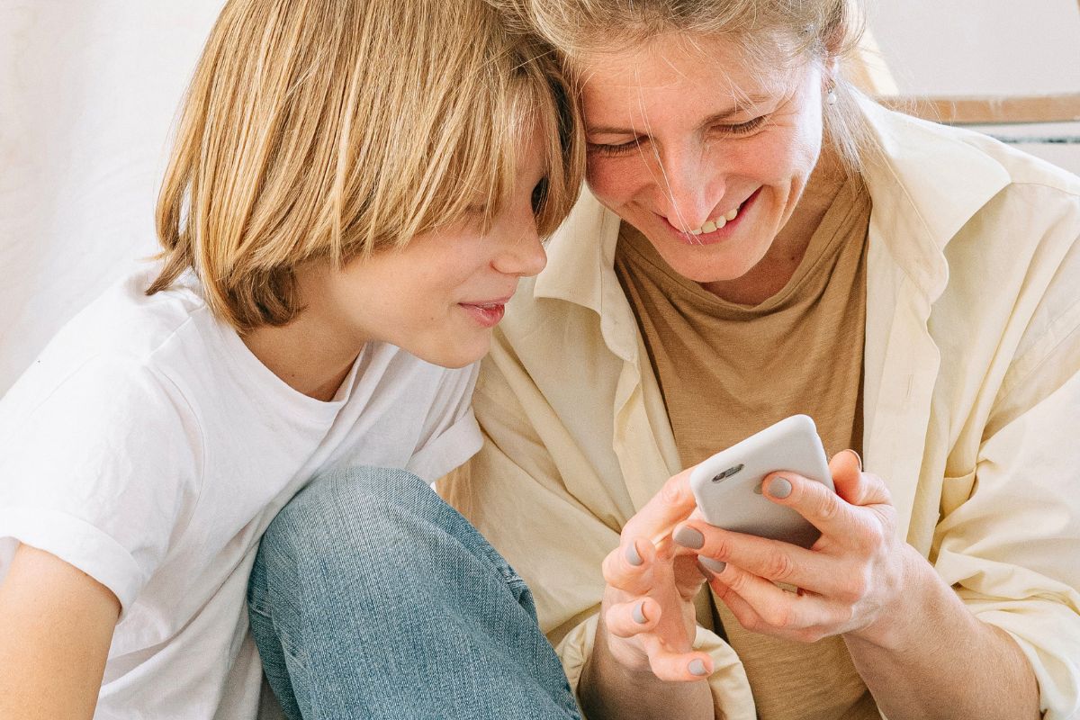 Parent and child using a phone together to build healthy tech habits.