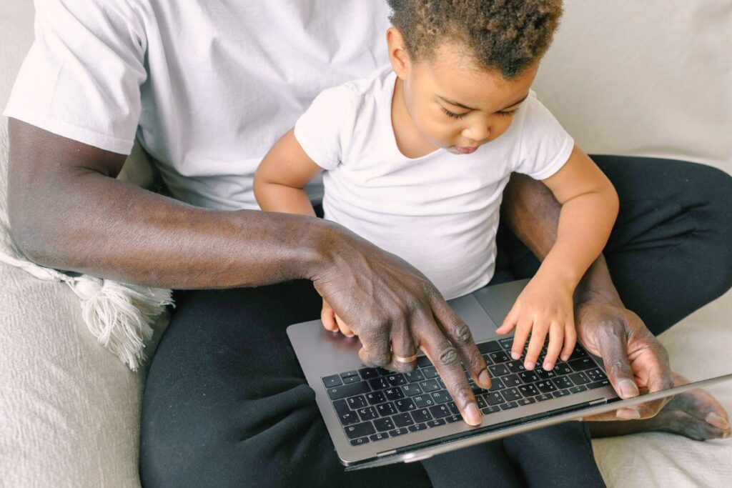 Parent guiding a young child through homework on a laptop using ChatGPT as a learning assistant.