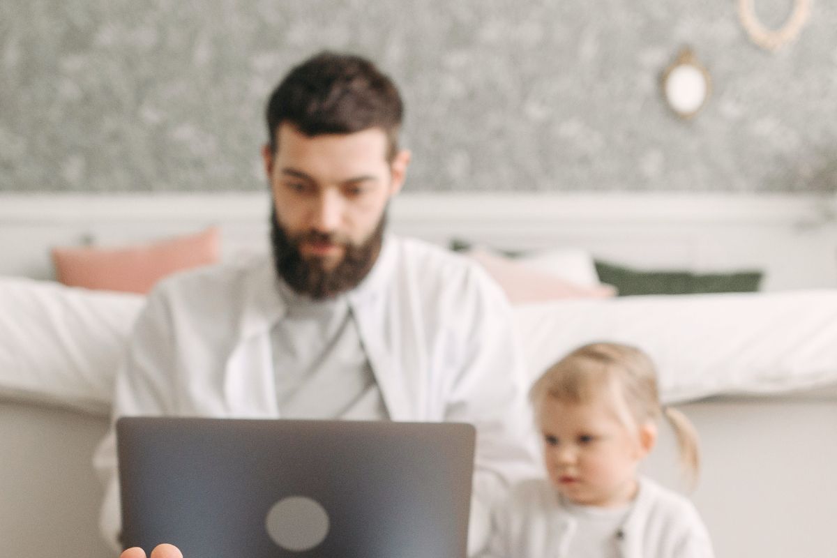 Dad working beside a young child using a laptop during homework time with ChatGPT for extra learning support.