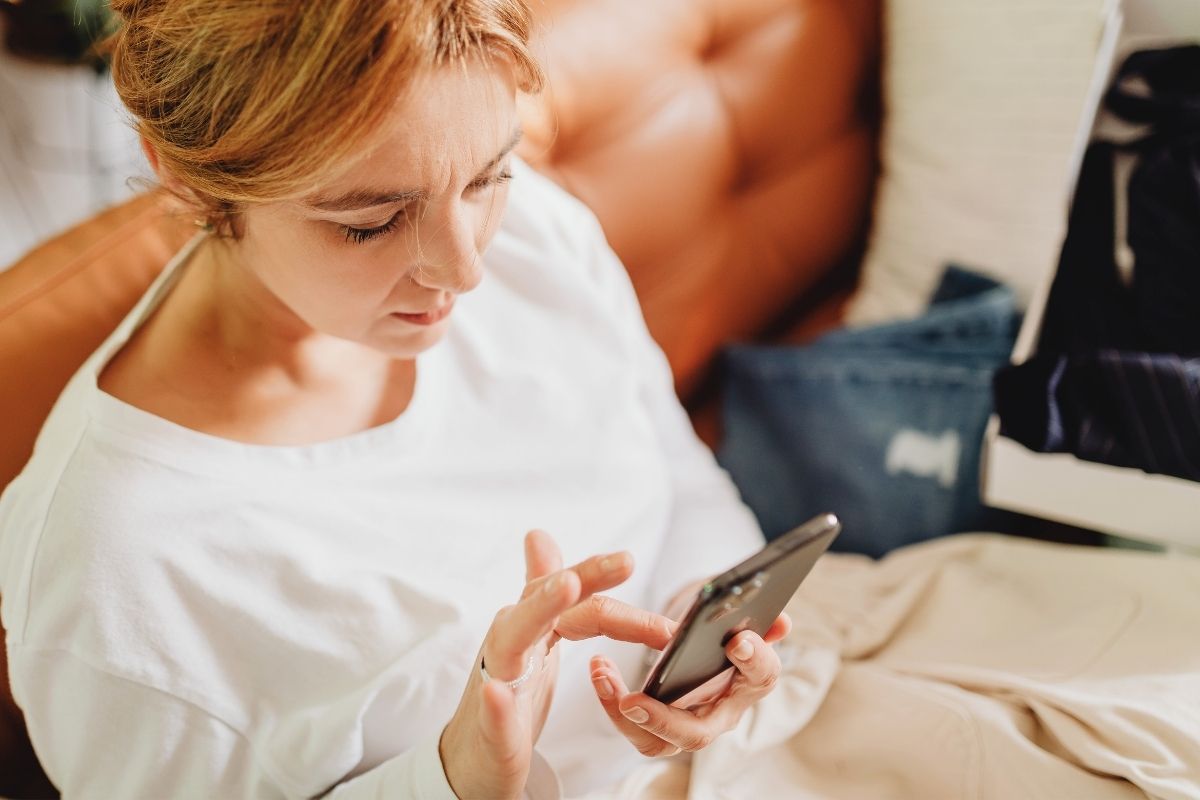 Busy parent using ChatGPT on a smartphone to find quick homework help and learning ideas before helping their child with schoolwork.