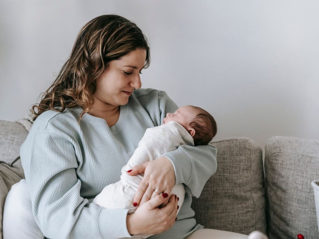 mother carrying her baby while sitting on a couch