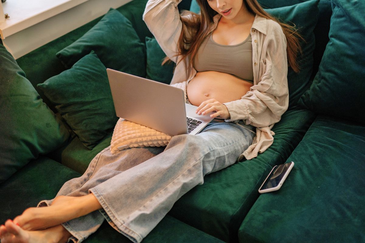 Pregnant woman using a laptop at home while learning natural ways to reduce stress during pregnancy.