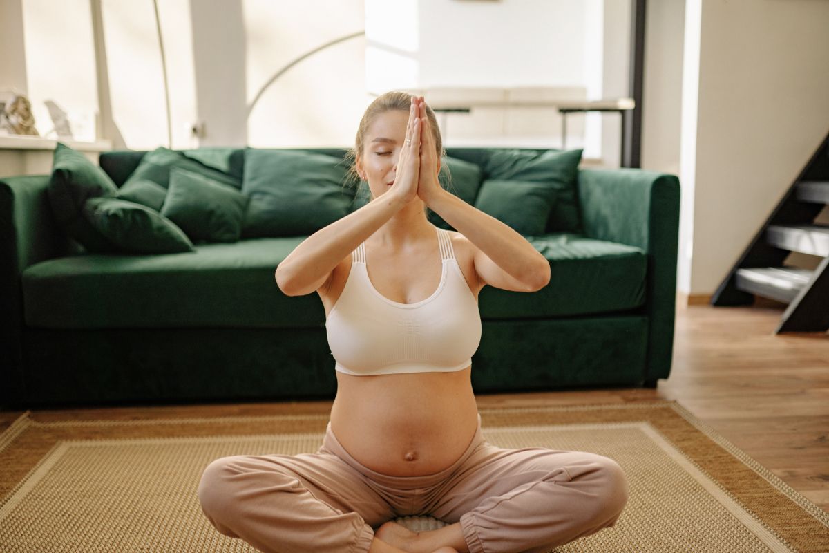 Pregnant woman doing breathing exercises at home as a simple pregnancy stress relief technique.